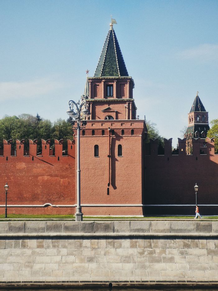 View of the Kremlin's red brick towers in Moscow under a clear blue sky.
